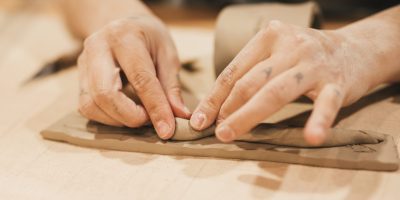 close-up-woman-s-hand-molding-clay-wooden-table